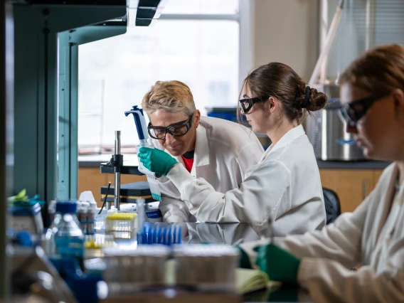 Student showing micropipette to instructor in lab environment