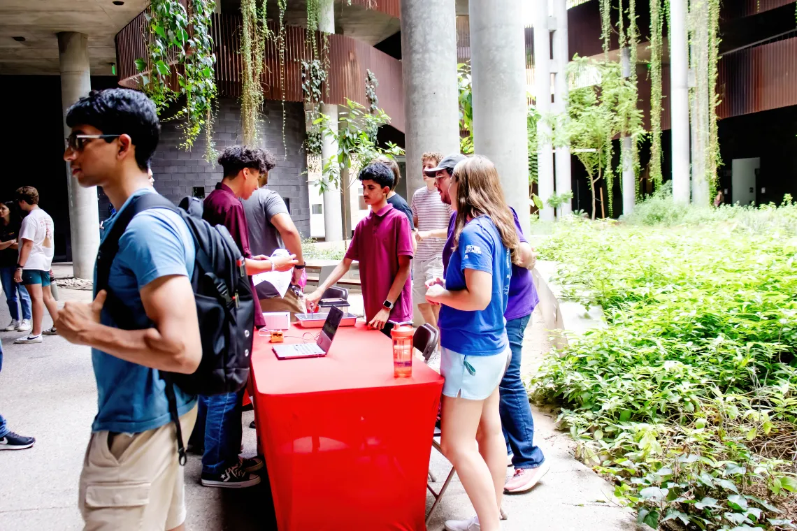 Welcome Event with students standing behind a table interacting with other students in the ENR2 courtyard