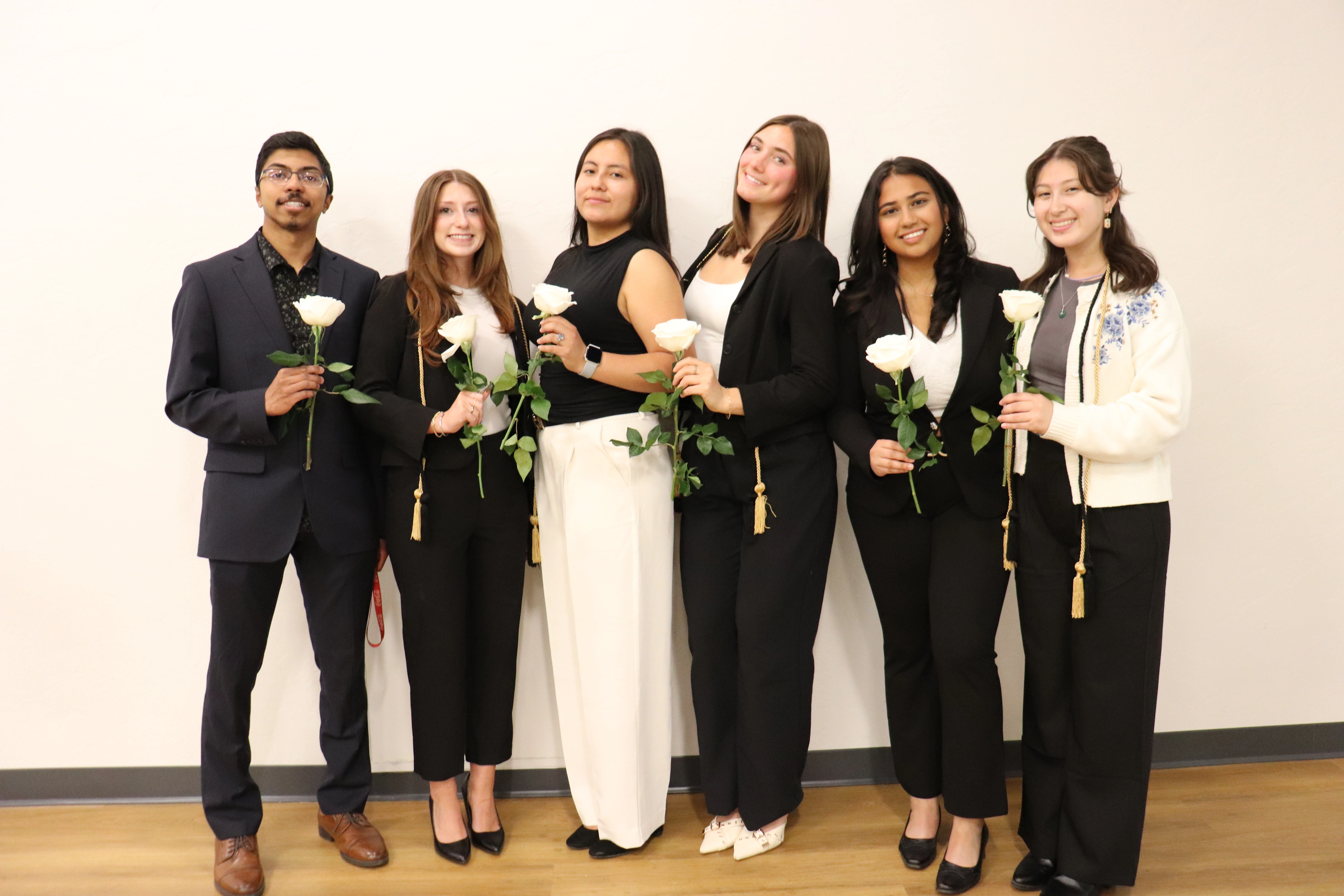 8 Nu Rho Psi Student Gathered around each holding a white rose
